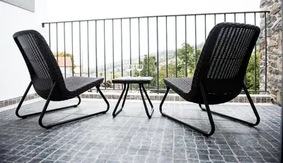 two chairs and a stool sitting on a balcony at Vila Maria Quinta 2 