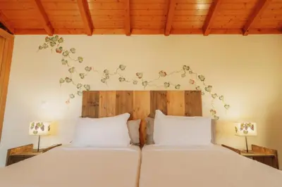 a bedroom with two beds with white sheets and flowers on the wall at Vila Maria Quinta 2 