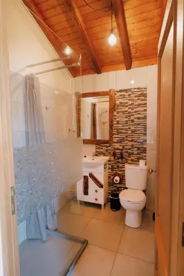 a bathroom with a toilet and a stone wall at Vila Maria Quinta 1 