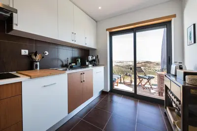 a kitchen with white cabinets and a large window at maresoul - Ferienapartment soul in Raposeira