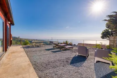 a patio with a table and chairs and the ocean at Madeira Sunset Cottage - Nature Retreat in Ponta do Pargo