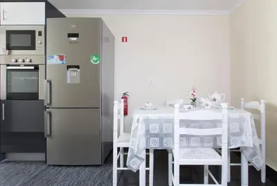 a kitchen with a table and a refrigerator at Antonella Home Funchal in Funchal