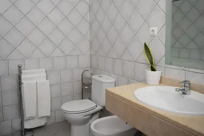 a white bathroom with a toilet and a sink at São Martinho, a Home in Madeira in Funchal