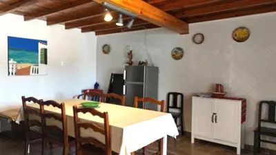 a kitchen with a table and chairs and a refrigerator at Casa d'Avó in Carrapateira