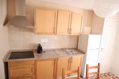 a kitchen with wooden cabinets and a sink and a refrigerator at Salema Beach Home in Salema