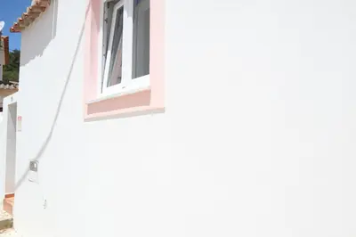 a window on the side of a white building at Salema Beach Home in Salema