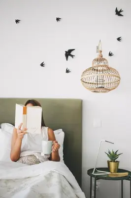a woman laying in bed reading a book and a bird at Casa LNNoa Boutique Room whit private pool in Lagos
