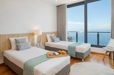 two beds in a room with a view of the ocean at Vila Papagaio Verde by An Island Apart in Funchal