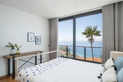a bedroom with a bed and a view of the ocean at Vila Papagaio Verde by An Island Apart in Funchal