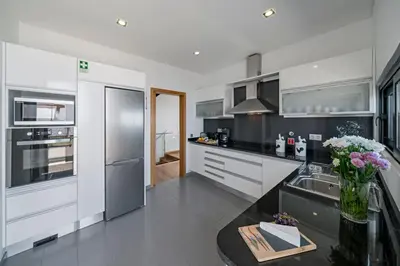 a kitchen with stainless steel appliances and a black counter top at Vila Papagaio Verde by An Island Apart in Funchal