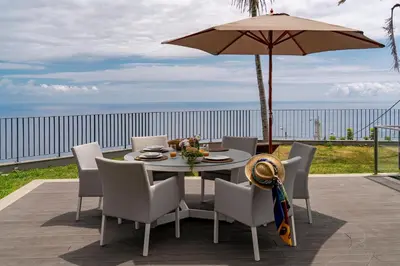 a table with chairs and an umbrella on a patio at Vila Papagaio Verde by An Island Apart in Funchal