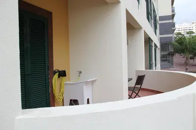 a white building with a yellow door and a chair at Doca do Cavacas Apartment in Funchal