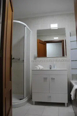a bathroom with a sink and a shower and a mirror at Doca do Cavacas Apartment in Funchal