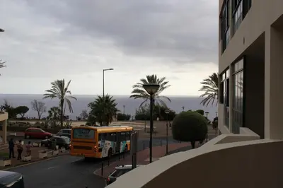 an orange bus is parked on a street near the ocean at Doca do Cavacas Apartment in Funchal
