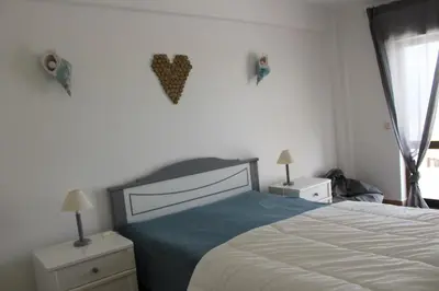 a bedroom with a bed and two night stands and a window at Beach Front Apartment 2 in Sagres