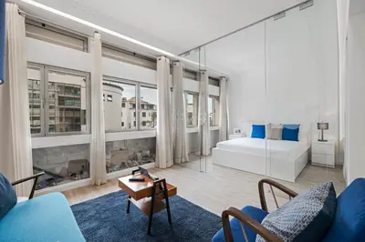 a living room with a couch and a bed and windows at Drapes Design Apartments by An Island Apart in Funchal