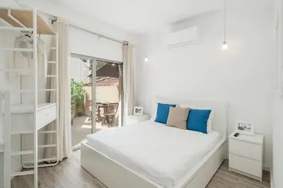 a white bedroom with a bed with blue pillows at Drapes Design Apartments by An Island Apart in Funchal
