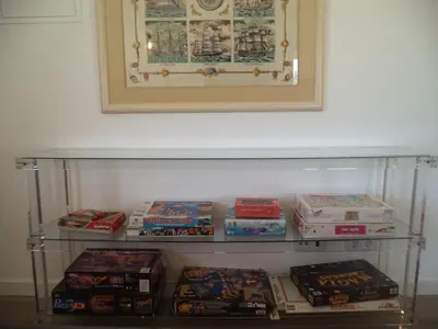 a shelf full of video games sitting under a painting at Casa do Tonel in Sagres