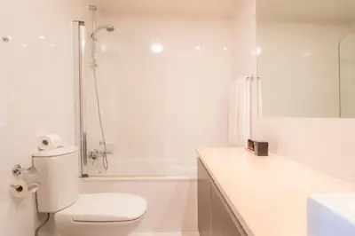 a white bathroom with a toilet and a shower at Luz casas- BayLuz apart,pool,beach, tennis, wifi,aircon in Luz