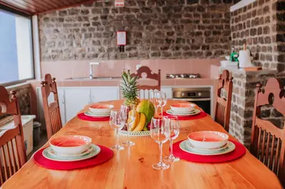 a wooden table with plates and wine glasses on it at Casa da Morena by Amazing Madeira in Santa Cruz