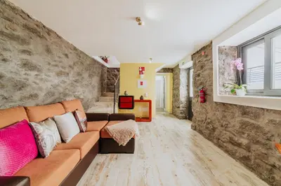a living room with a couch and a stone wall at Casa da Morena by Amazing Madeira in Santa Cruz