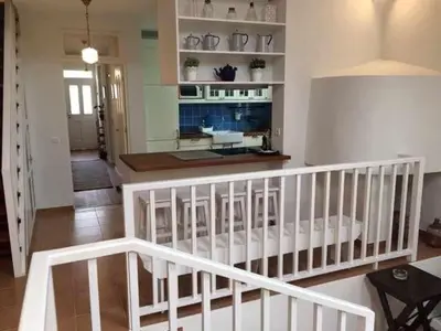 a living room with a white staircase and a kitchen at GuestReady - Casa Avó Alice in Porto da Cruz