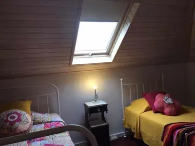 a bedroom with two beds and a skylight at GuestReady - Casa Avó Alice in Porto da Cruz