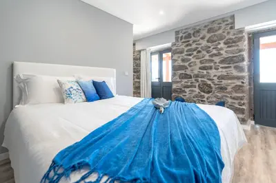 a bedroom with a large bed with a stone wall at Casa Mariana by Rent2U, Lda in Arco da Calheta