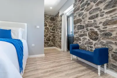 a bedroom with a stone wall and a blue chair at Casa Mariana by Rent2U, Lda in Arco da Calheta