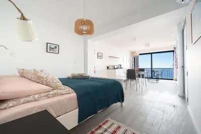 a bedroom with a bed and a living room with a view at Seasky Arco in Arco da Calheta