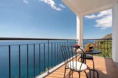 a balcony with a table and chairs and the ocean at Seasky Arco in Arco da Calheta