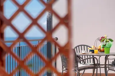 a table and chairs on a balcony with a window at Seasky Arco in Arco da Calheta