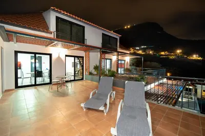 a patio with two chairs and a table on a house at Seasky Arco in Arco da Calheta