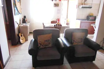 a living room with two chairs and a guitar at Charming house in Machico with mountain view and garden in Machico