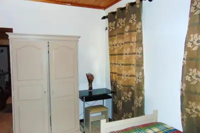 a bedroom with a closet and a table and curtains at Charming house in Machico with mountain view and garden in Machico
