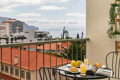 a table with a book and bread on a balcony at Ilhéus IV by An Island Apart in Funchal