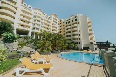 a resort with a swimming pool and chairs and buildings at Cliff by Madeira Best Apartments in Funchal