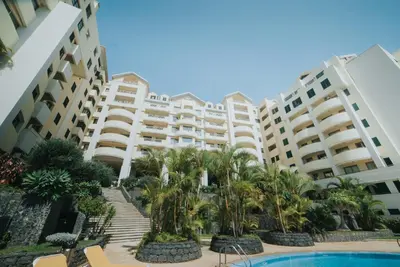 a resort with a pool and palm trees and buildings at Cliff by Madeira Best Apartments in Funchal