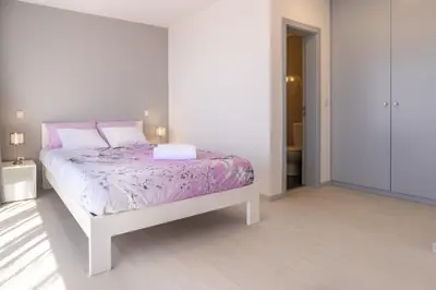 a white bedroom with a bed with purple sheets and pillows at Casa Campos , Modern two bedroom house in Loreto in Achada de Cima