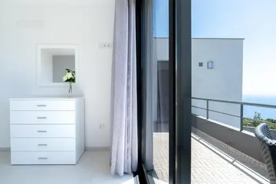 a bedroom with a white dresser and a balcony at Casa Campos , Modern two bedroom house in Loreto in Achada de Cima
