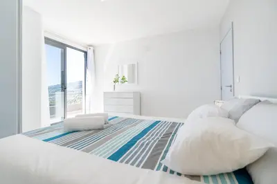 a white bedroom with a large bed and a large window at Casa Campos , Modern two bedroom house in Loreto in Achada de Cima