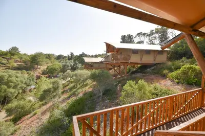 a house on the side of a hill with trees at Salema Eco Camp - Sustainable Camping & Glamping in Salema