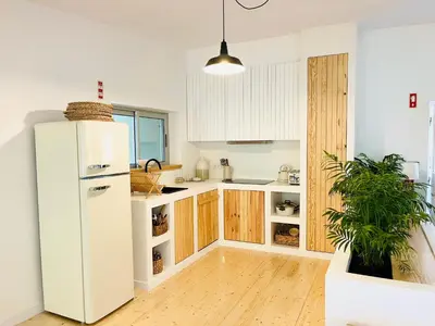 a kitchen with a white refrigerator and wooden cabinets at Salema Eco Camp - Sustainable Camping & Glamping in Salema