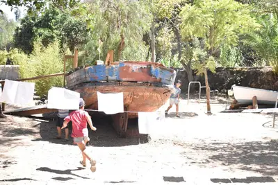 two children running in front of an old boat at Salema Eco Camp - Sustainable Camping & Glamping in Salema