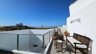 a balcony with two chairs and a glass box at Sea View Apartment Carrapateira in Carrapateira