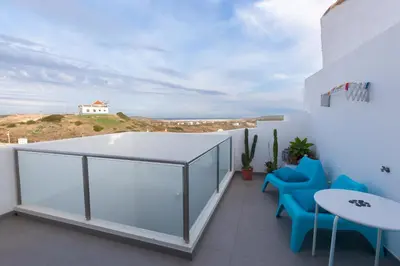 a balcony with blue chairs and a view of the ocean at Sea View Apartment Carrapateira in Carrapateira