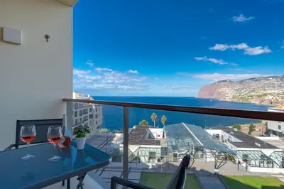 a balcony with two wine glasses and a view of the ocean at Centromar Residence Ocean View By Atlantic Holiday in Funchal