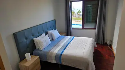 a bedroom with a bed with a blue headboard and a window at CRISTO REI APARTMENT in Caniço