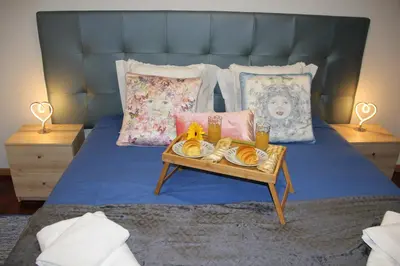 a bed with a tray of food on a table at CRISTO REI APARTMENT in Caniço