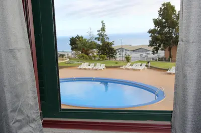 a view of a swimming pool from a window at CRISTO REI APARTMENT in Caniço